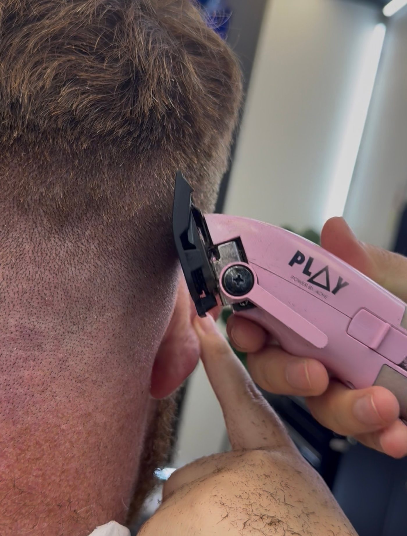 Barber scissor-cutting and shaping a client's hair with a comb